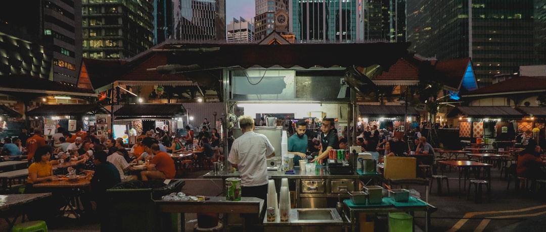 A group of friends enjoys hawker food at a  street stall, a highlight of any day trips from Singapore across the Causeway.
