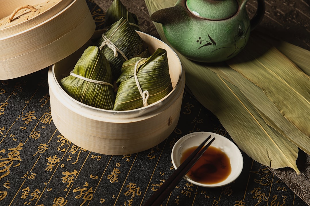 A chef carefully wrapping rice dumplings in bamboo leaves at a Singapore restaurant