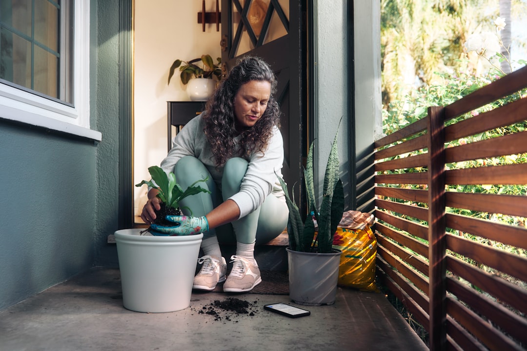 A person placing native tropical plants in containers on a high-rise Singapore balcony, urban outdoor space.