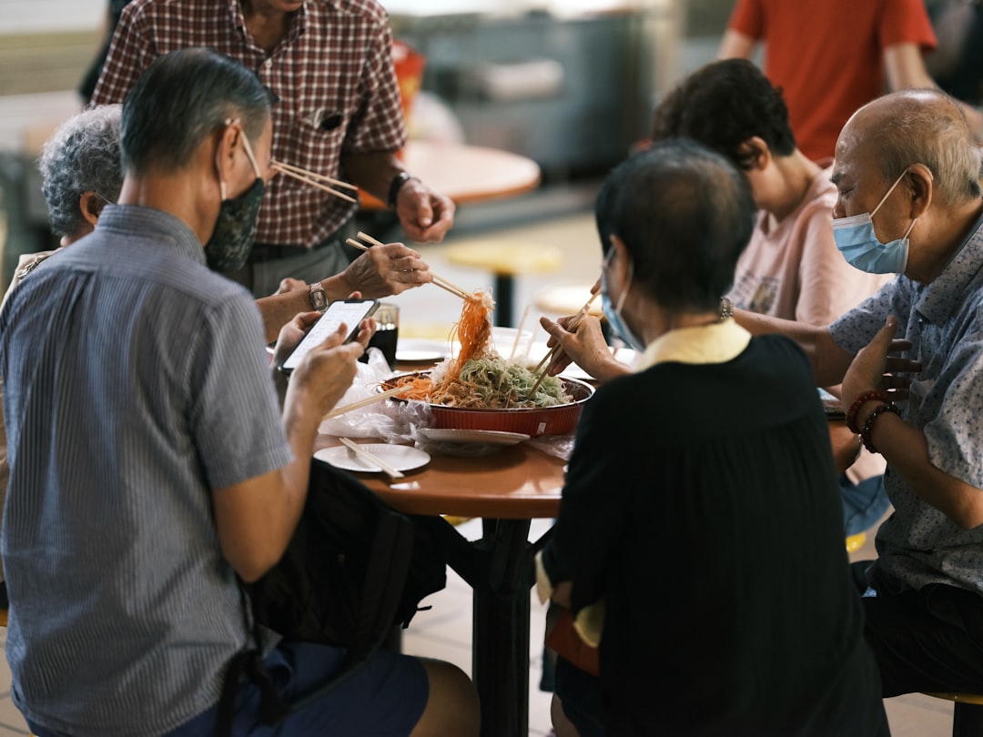 A group of friends sharing laksa stalls dishes at an outdoor Singapore hawker centre
