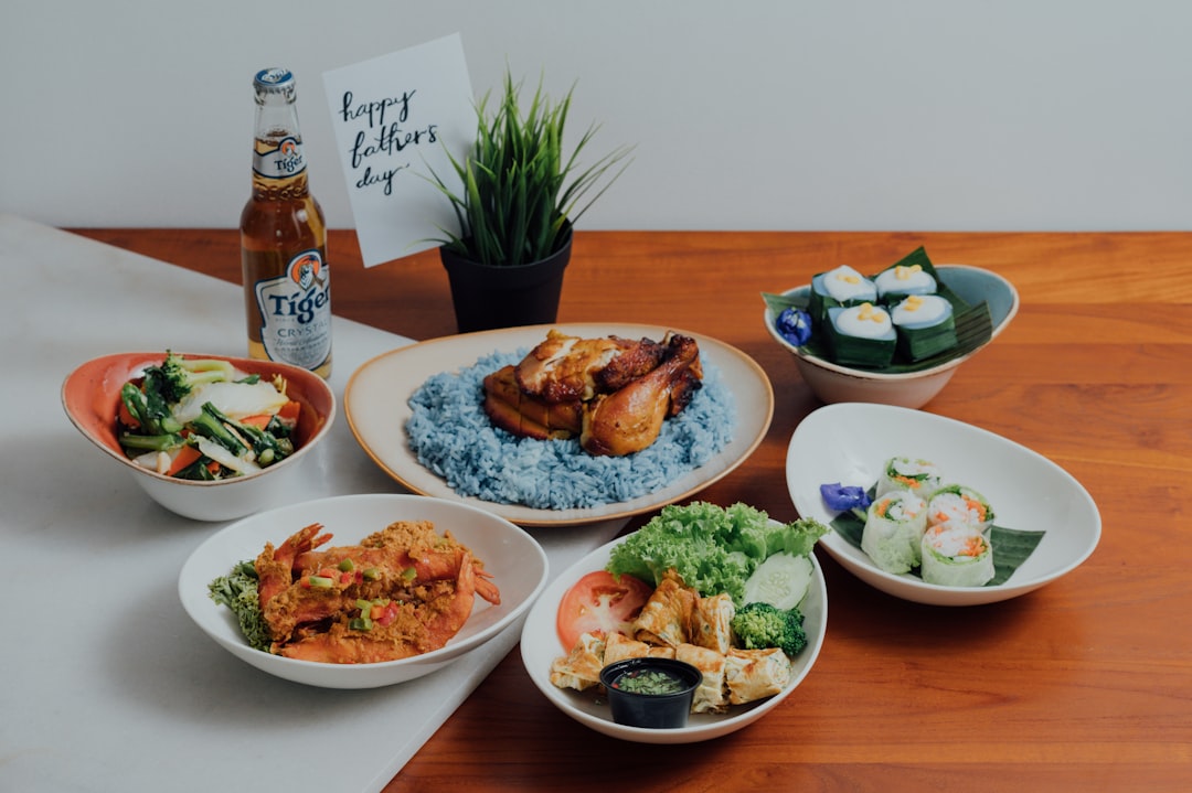 A family gathers around a table of National Day dishes including chilli crab and satay at a Singapore celebration.