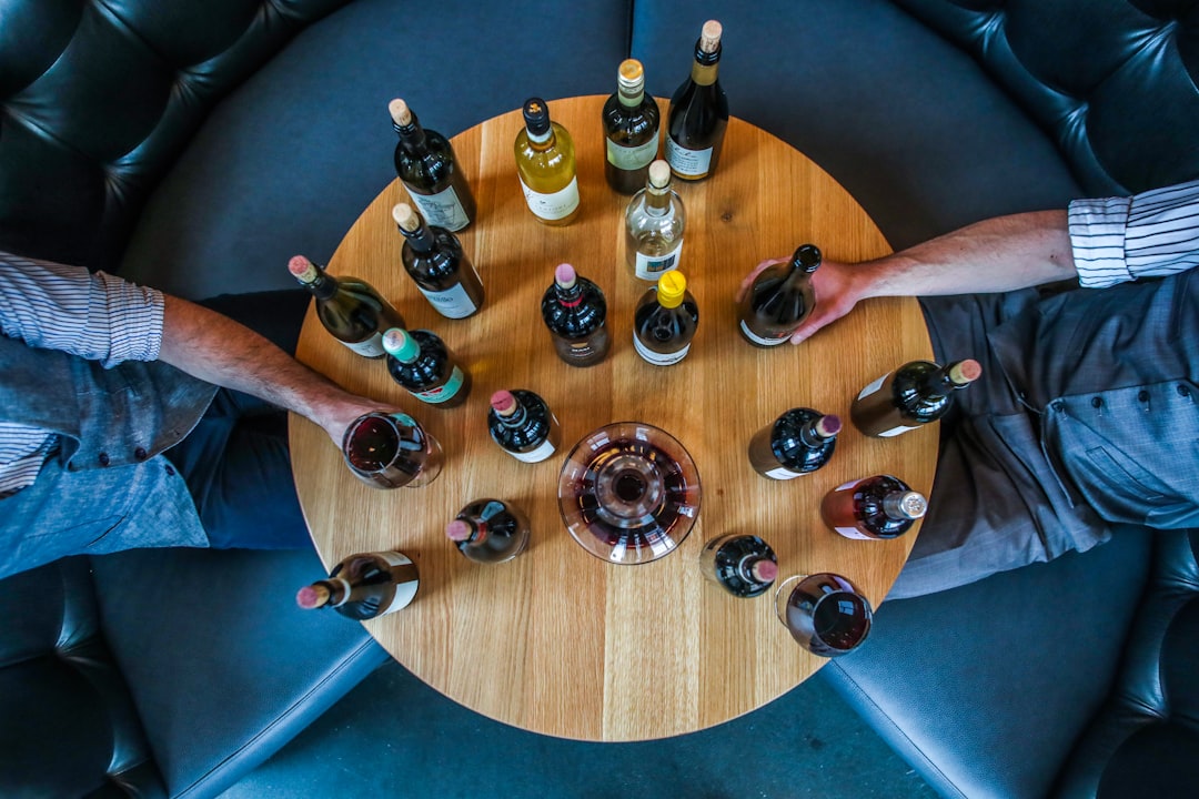 A wine collector sits at a tasting table in a private cellar space in Singapore, examining a glass of aged red wine