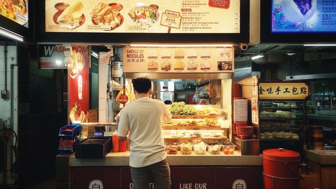 A man selecting dishes from a Singapore vegetarian hawker stall serving mock-meat options