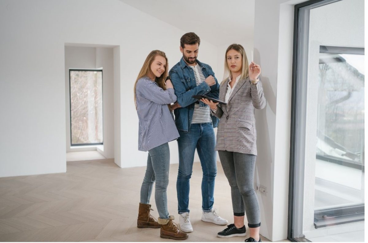A couple meets with an estate agent inside a London property, discussing long-term investment options