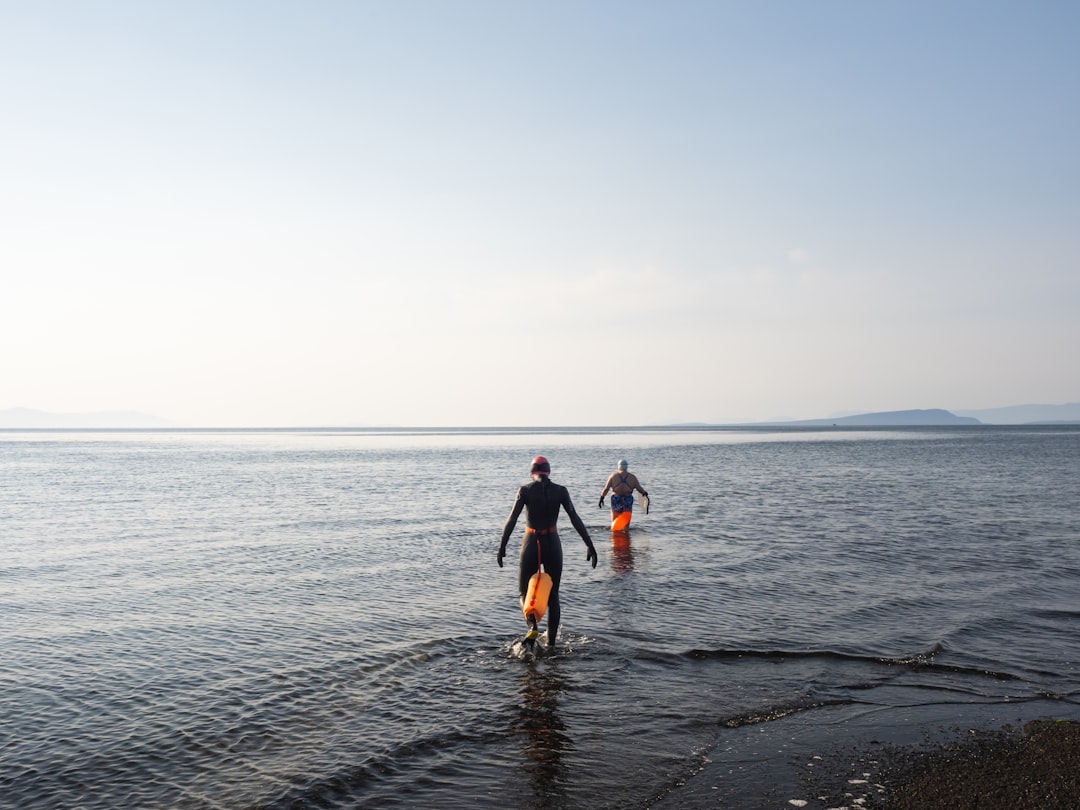 A person wading into an open-air lake at dawn, capturing the calm of wild swimming in the city