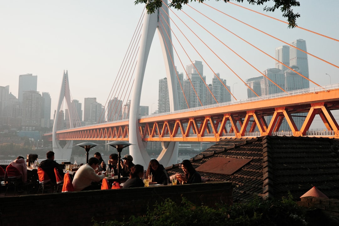 A group of friends laughing together on a rooftop bar terrace with a wide city skyline view behind them.