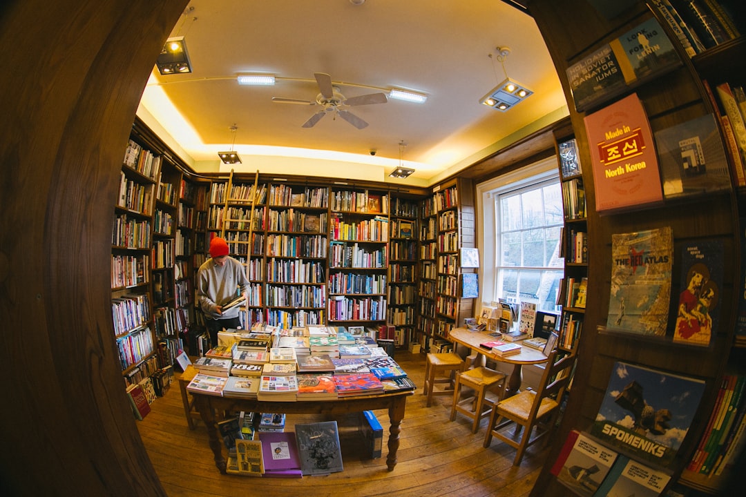 A bookseller hands a book recommendation to a customer inside a busy independent bookshop