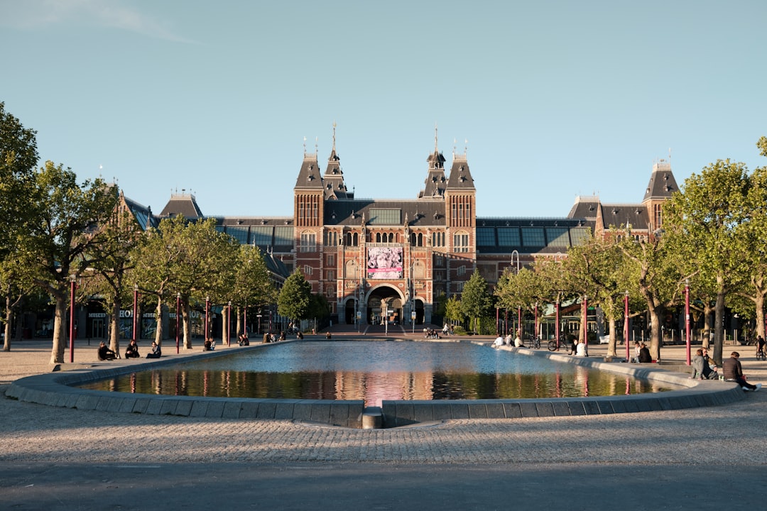 A group of friends laughing outside the Rijksmuseum in Amsterdam during a city break from London in summer
