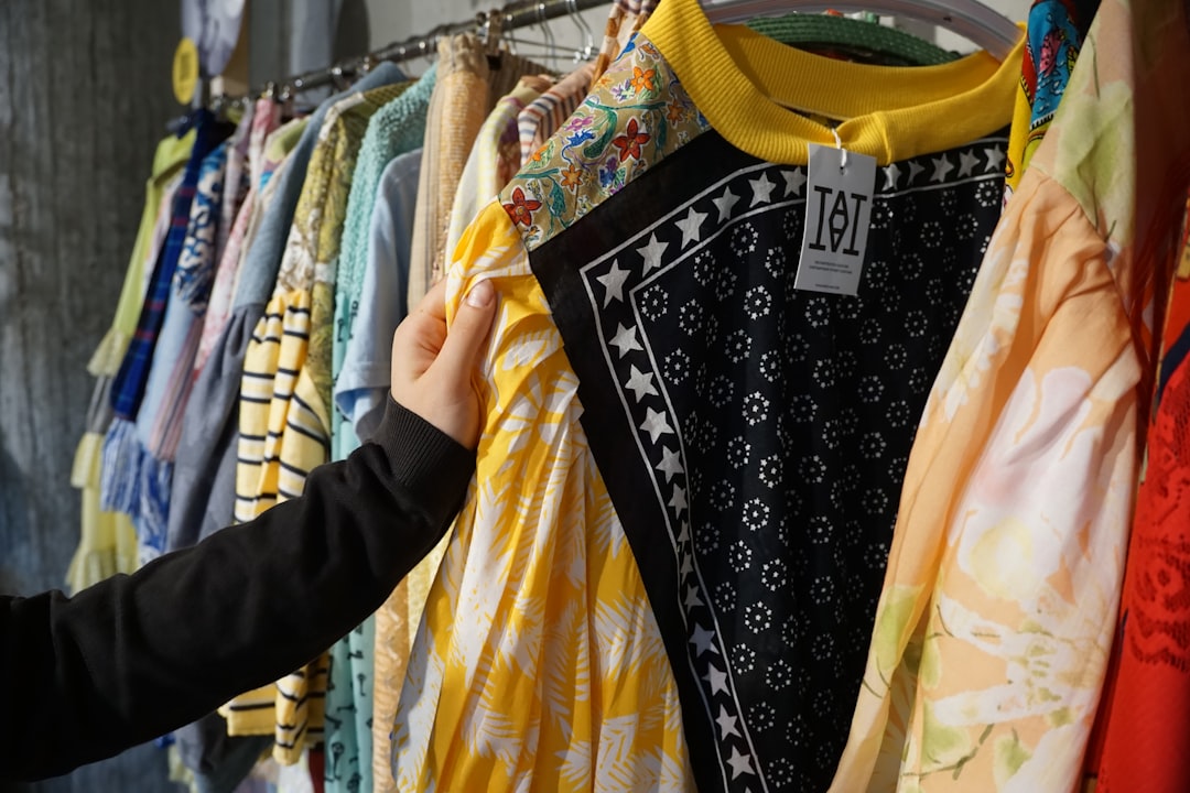 A person holding up a bright linen dress found while refreshing a summer wardrobe at a charity shop