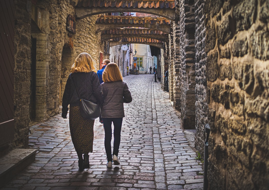 A couple walks along a cobblestone street lined with autumn leaves, enjoying one of the best weekend escapes by train.