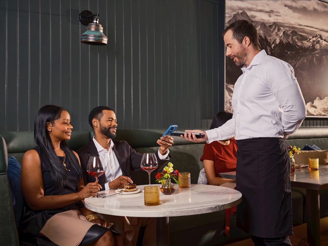 A waiter presents the menu to a guest seated in a formal private dining room at a London members' club