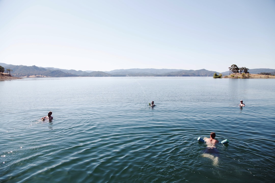 A group of club swimmers gathered at an outdoor lake for an open water swimming session in autumn