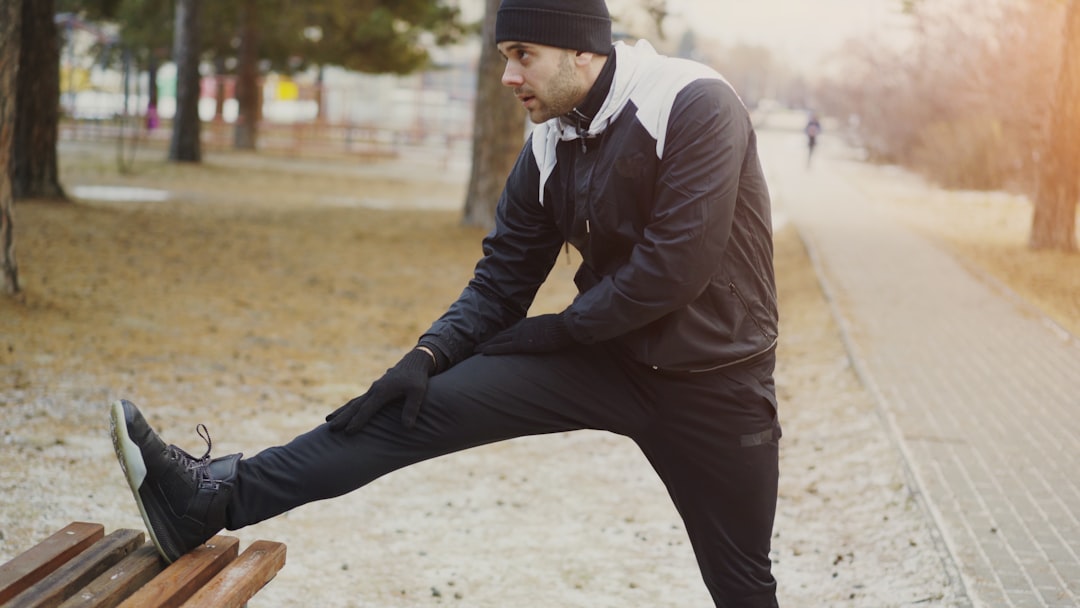 A person stretching on a park bench during an early morning routine surrounded by autumn foliage in London