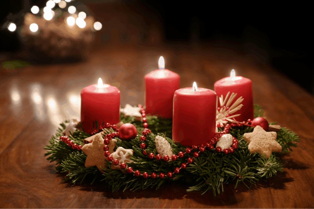 Minimalist Scandinavian advent decor wreath with four white candles on wooden table with pine branches
