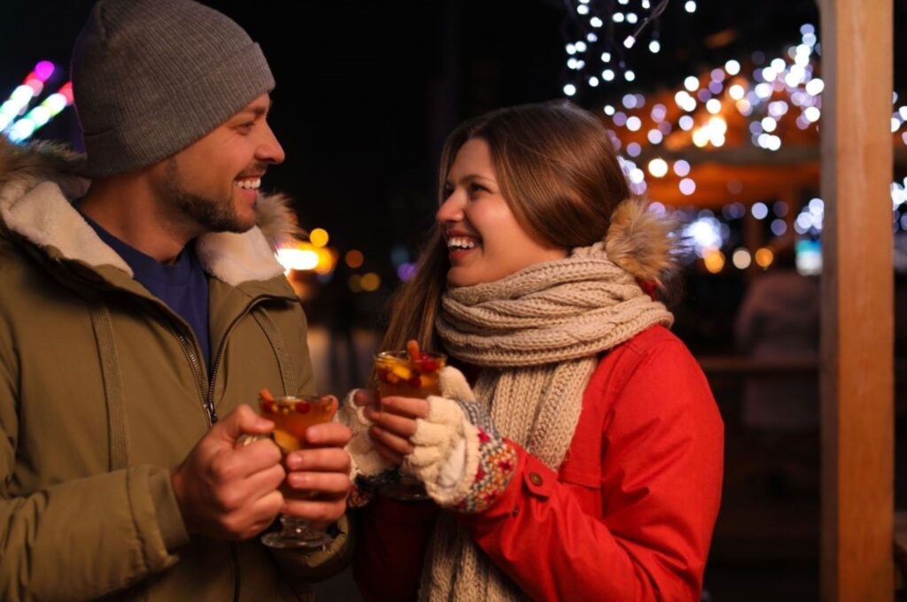 Steaming mugs of traditional mulled wine Glühwein at European Christmas markets during winter evening, representing festive beverages and cozy holiday atmosphere across Europe's best markets