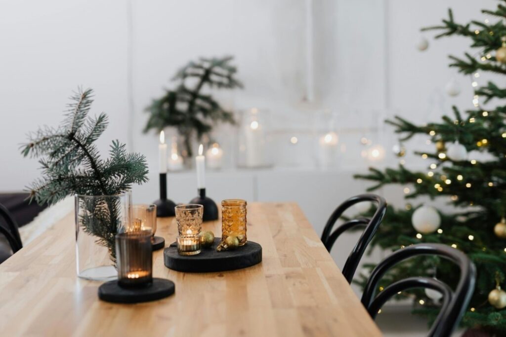 Cozy Scandinavian Christmas decor featuring candles, natural pine greenery, and linen textiles on dining table, showcasing hygge atmosphere with warm lighting and minimalist Nordic styling