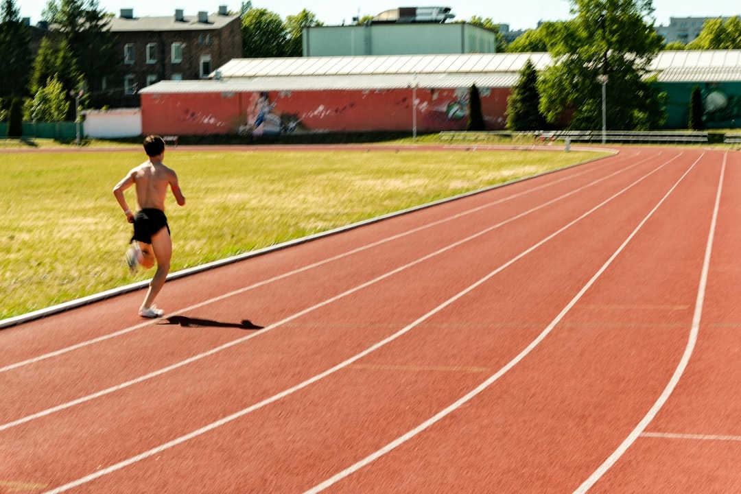 A sprinter crosses the finish line at an open-air sporting events championship under a bright summer sky