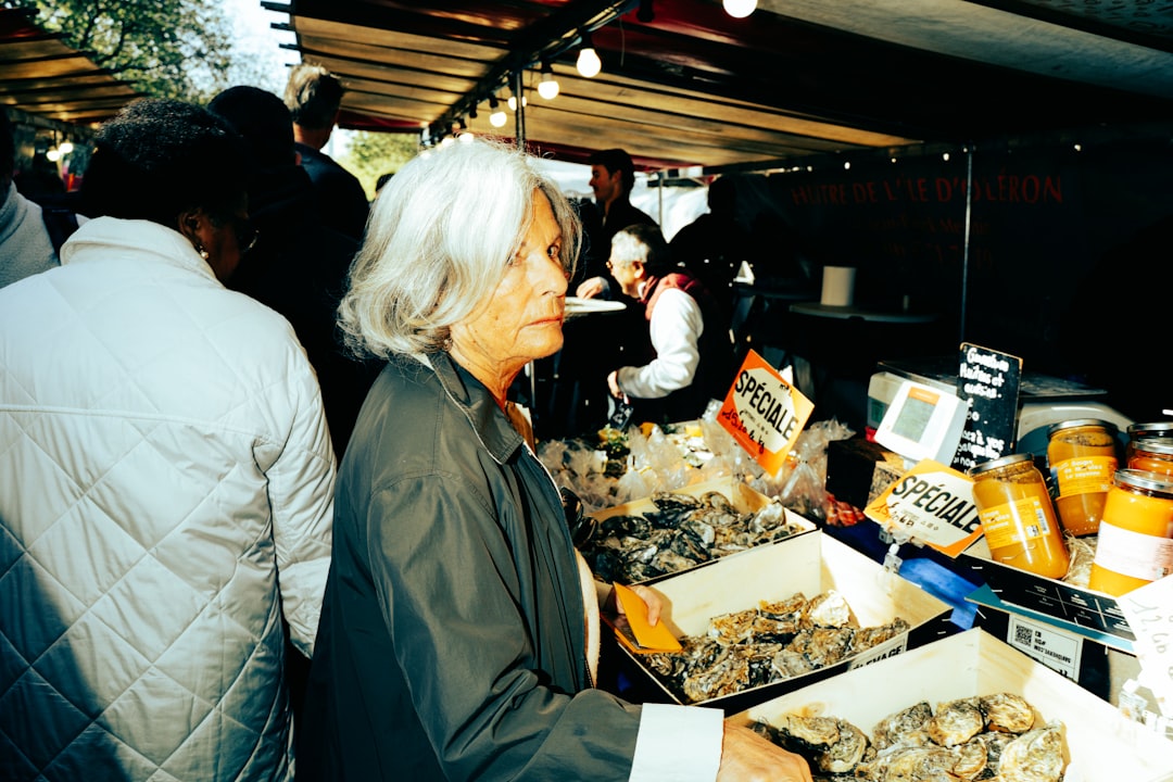 A woman browsing an artisan food stall at a European market, discovering regional EU geographical indication products.