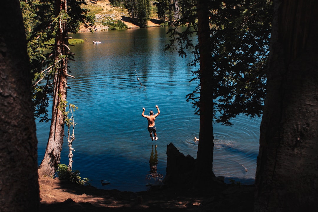 A male athlete adjusting his goggles before starting an open-water swimming session at a certified EU inland bathing site.