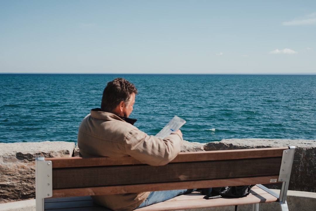 A man reading on a wooden dock at an EU lakeside retreat in late August afternoon light