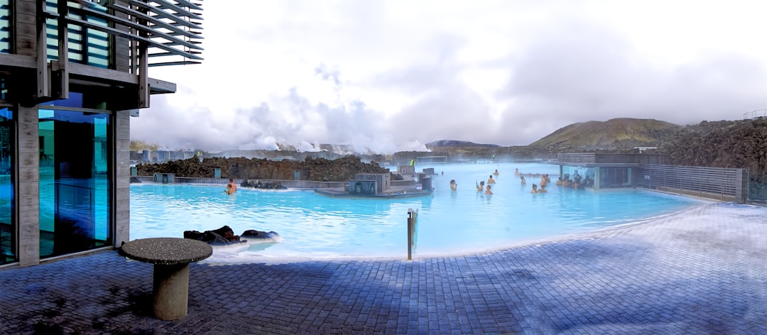 A couple shares a quiet moment in an outdoor thermal pool at a private EU thermal retreat, the water glowing warm.