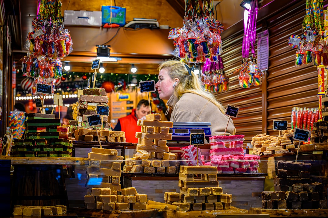 A woman selects artisan local cheeses to pair with EU wines at a traditional European market stall