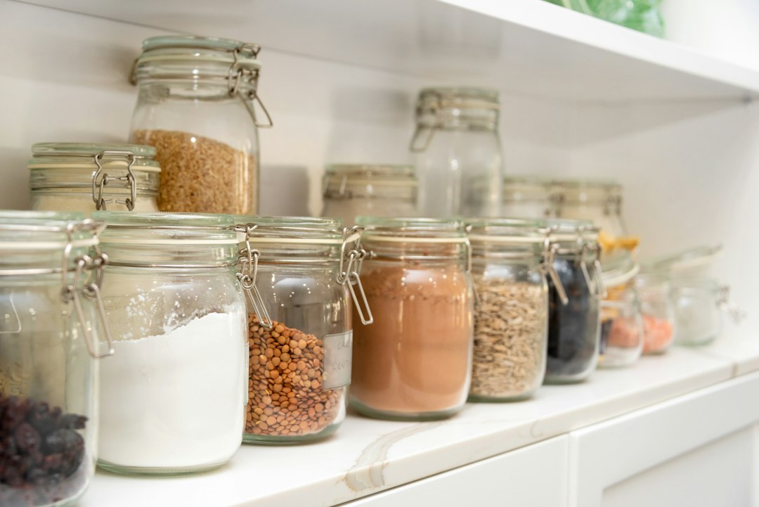 A person organising a selection of gluten-free flours in labelled jars on a rustic European kitchen shelf