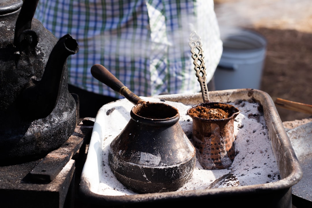 A person measuring and grinding coffee beans at home as part of a South Indian filter coffee brewing ritual