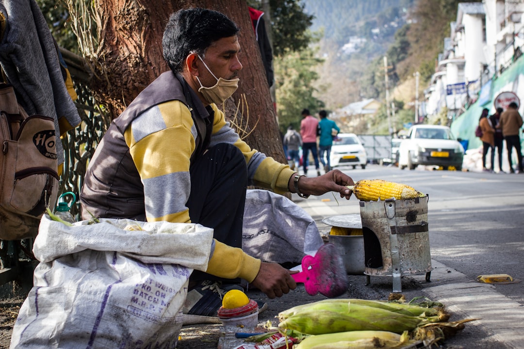 A man holds a freshly roasted bhutta topped with lemon and masala, one of the most iconic monsoon street food.